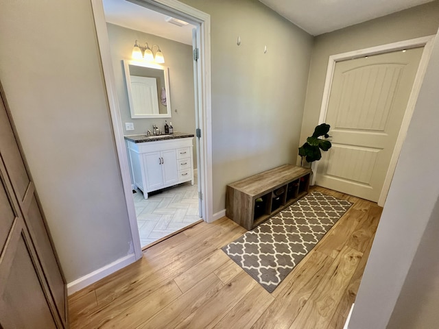 interior space with a sink, baseboards, and light wood-type flooring