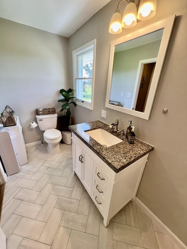 half bathroom featuring baseboards, toilet, and vanity