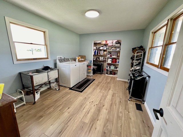 washroom with light wood-style flooring, washer and dryer, laundry area, and visible vents