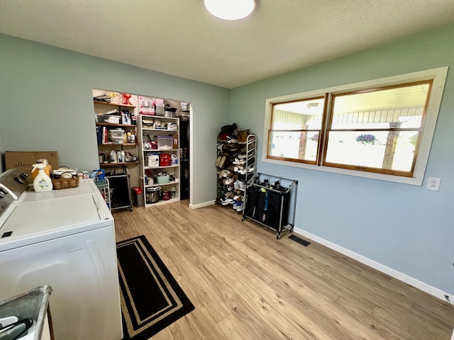 washroom featuring baseboards, separate washer and dryer, light wood-style floors, visible vents, and laundry area