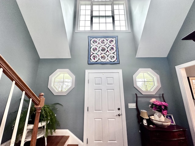 foyer entrance with a towering ceiling, baseboards, and stairway