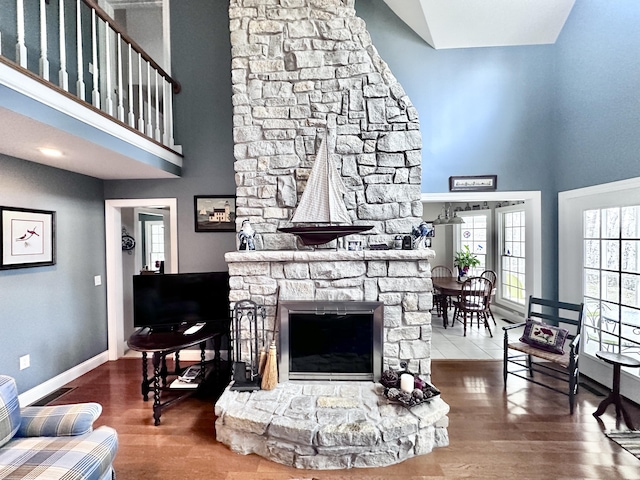 living room featuring a high ceiling, baseboards, a fireplace, and wood finished floors