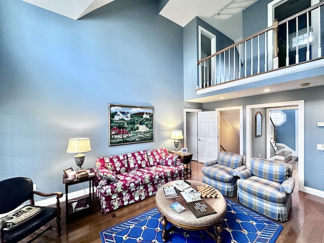 living area featuring stairway, a high ceiling, baseboards, and dark wood-type flooring