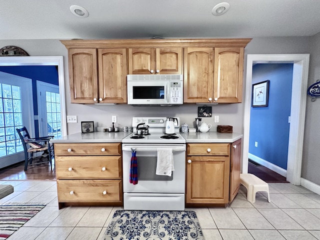 kitchen with white appliances, light tile patterned floors, baseboards, and light countertops