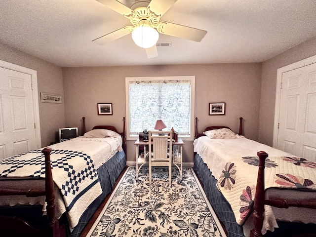 bedroom featuring baseboards, visible vents, ceiling fan, and a textured ceiling