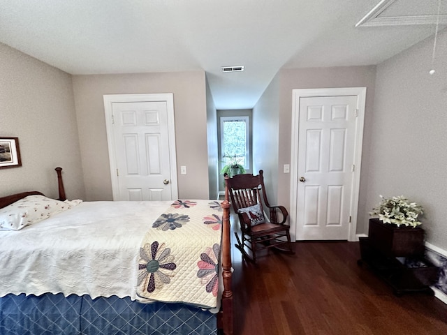 bedroom with dark wood-type flooring, visible vents, and attic access