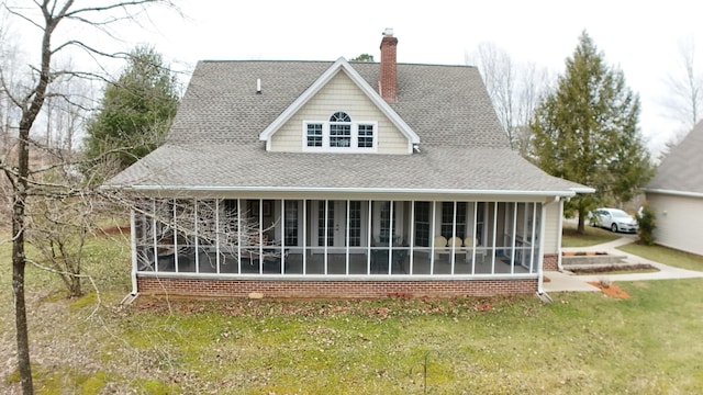 rear view of house with a shingled roof, brick siding, a lawn, and a chimney