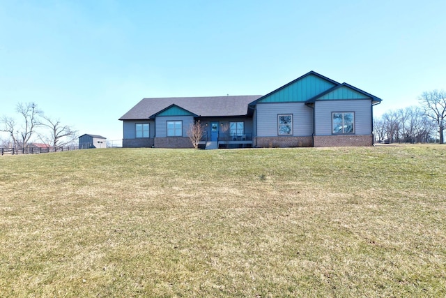 view of front of home with board and batten siding, a front yard, and brick siding