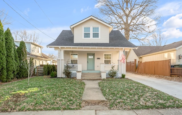 bungalow-style home featuring brick siding, roof with shingles, fence, a porch, and a front yard