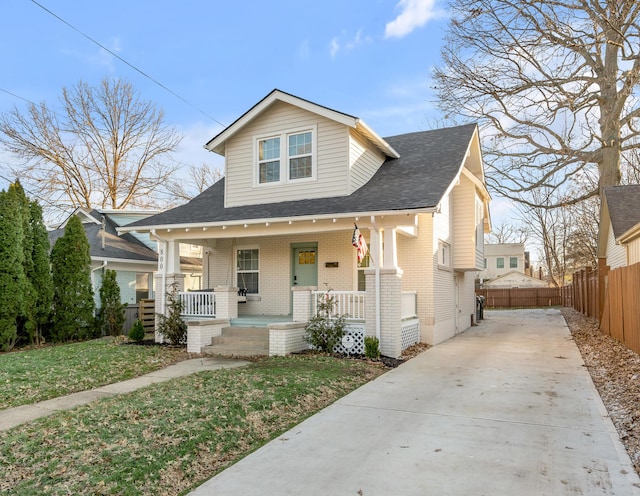 bungalow featuring a shingled roof, concrete driveway, fence, a porch, and brick siding