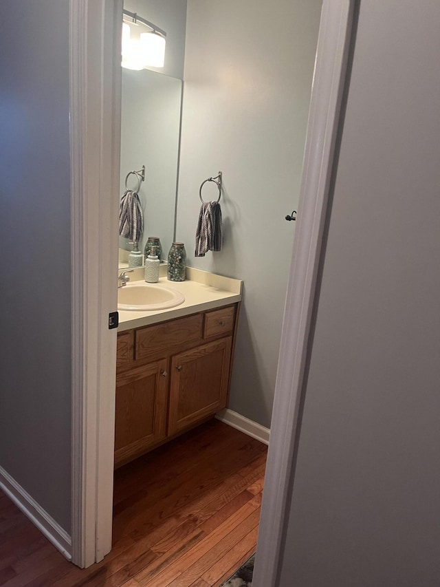 bathroom with baseboards, wood finished floors, and vanity