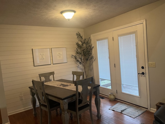 dining area with visible vents, baseboards, a textured ceiling, and dark wood finished floors