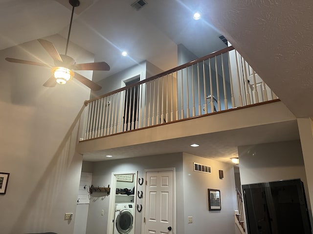 stairs with visible vents, washer / clothes dryer, a high ceiling, and ceiling fan