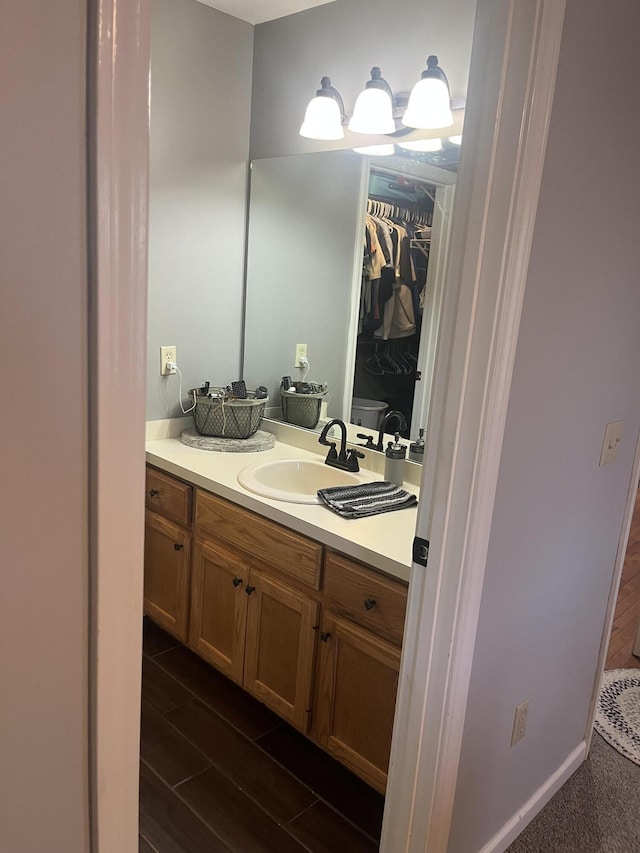 bathroom with vanity, a walk in closet, and wood finished floors