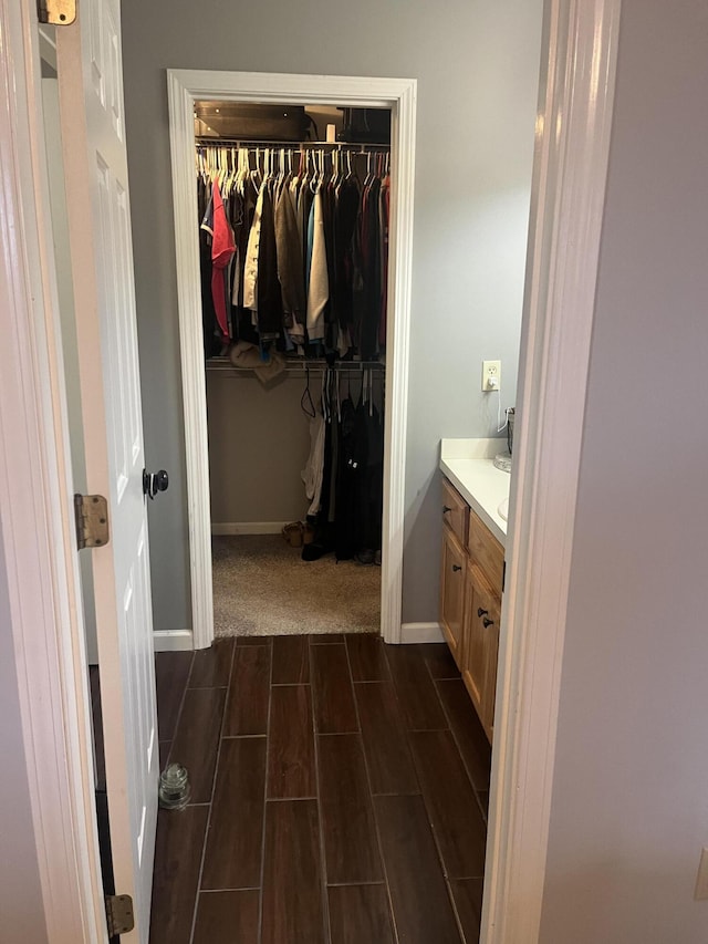 bathroom featuring vanity, a spacious closet, baseboards, and wood finish floors