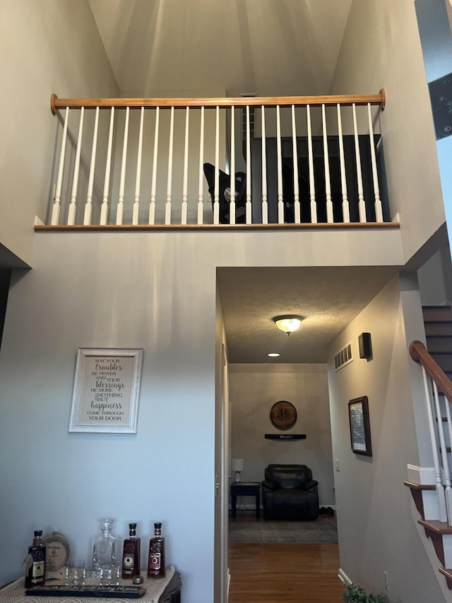 stairs with visible vents, a high ceiling, and wood finished floors