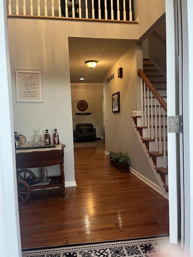 entryway with hardwood / wood-style flooring, stairway, baseboards, and visible vents