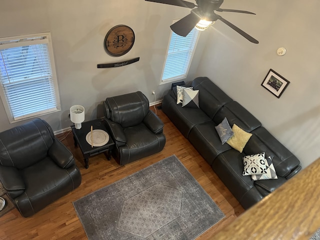 living area featuring baseboards, a ceiling fan, and wood finished floors