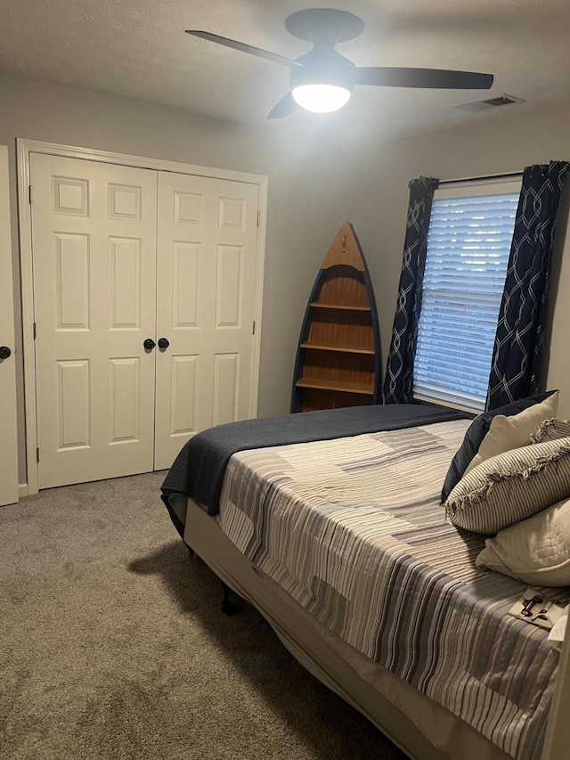 carpeted bedroom featuring a textured ceiling, visible vents, a closet, and ceiling fan