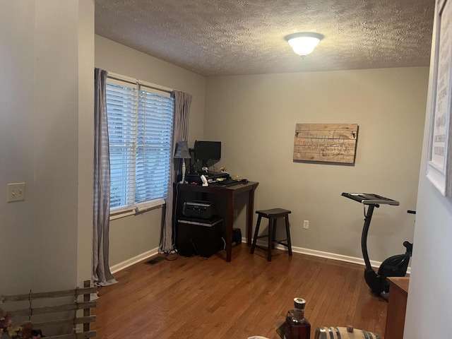 home office featuring baseboards, a textured ceiling, and wood finished floors