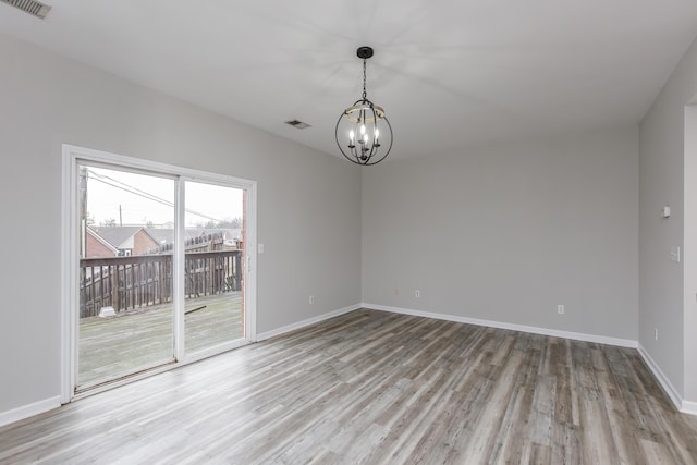 empty room with a chandelier and light hardwood / wood-style floors