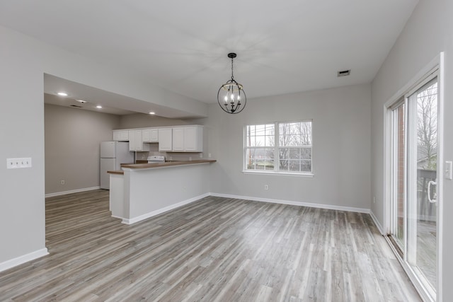 kitchen with plenty of natural light, kitchen peninsula, white cabinets, and white fridge