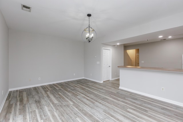 unfurnished room with a notable chandelier and light hardwood / wood-style floors