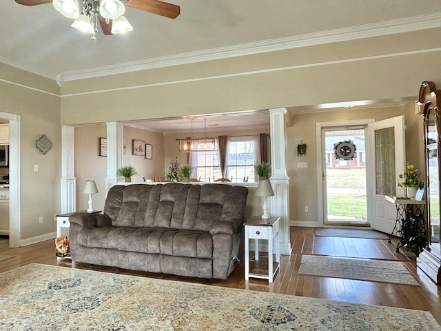 living room featuring decorative columns, crown molding, dark wood-type flooring, and ceiling fan