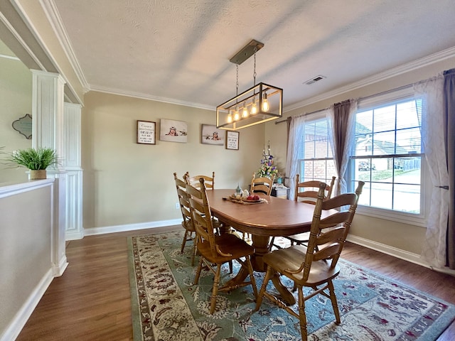 dining space with ornamental molding, dark wood-type flooring, and a textured ceiling