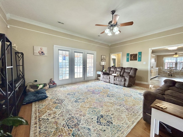 living room with ornamental molding, light hardwood / wood-style floors, and ceiling fan