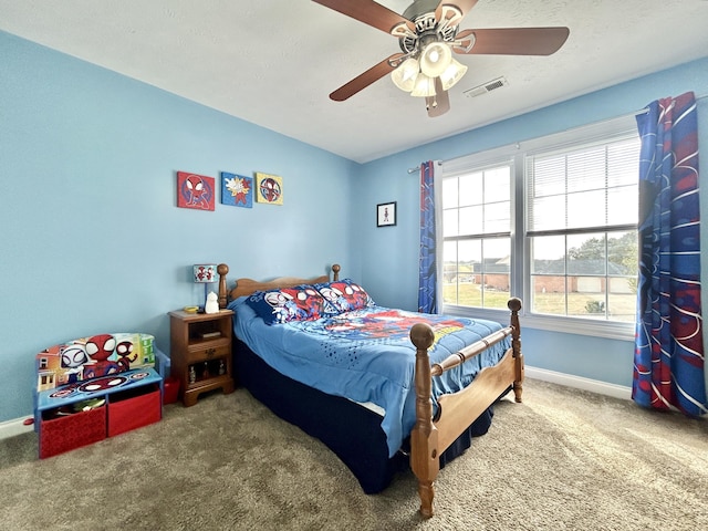 carpeted bedroom featuring ceiling fan and a textured ceiling