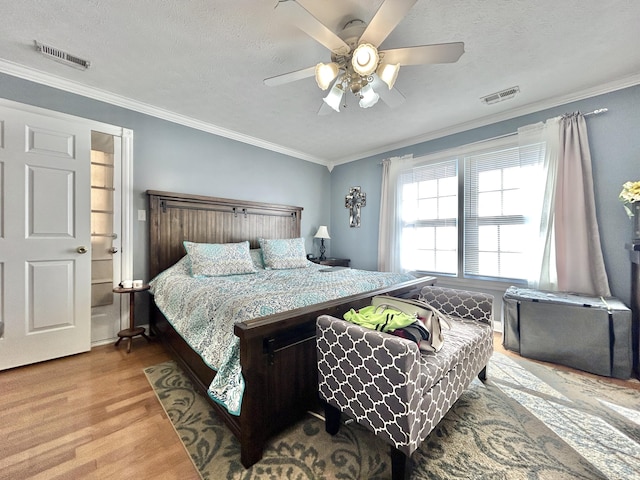 bedroom with crown molding, a textured ceiling, and light hardwood / wood-style floors