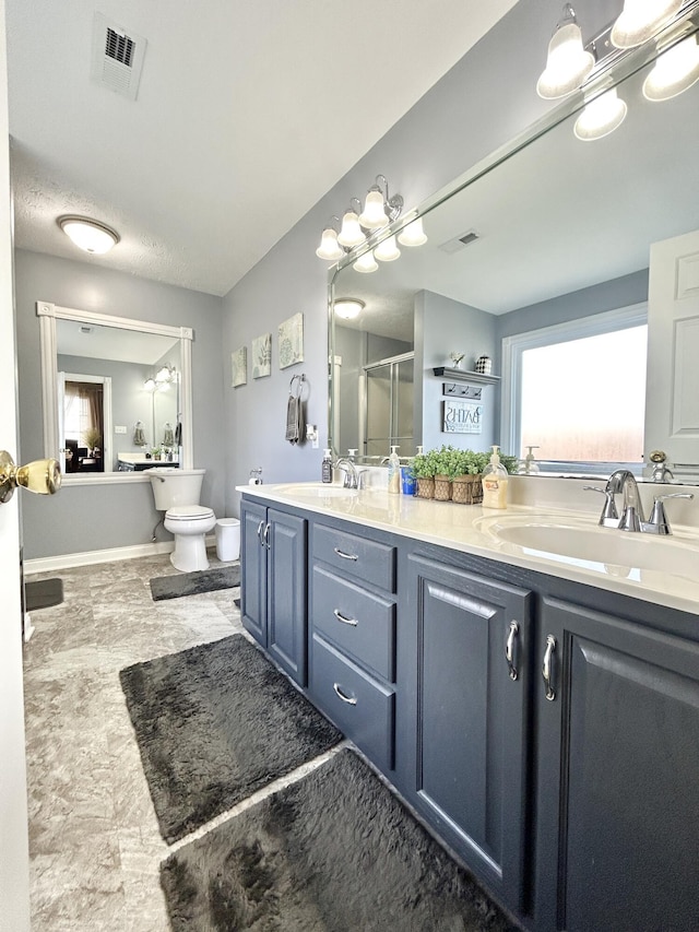 bathroom with a shower with door, vanity, and toilet