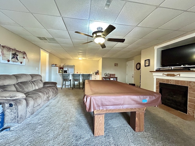 rec room with pool table, carpet floors, ceiling fan, a fireplace, and a drop ceiling