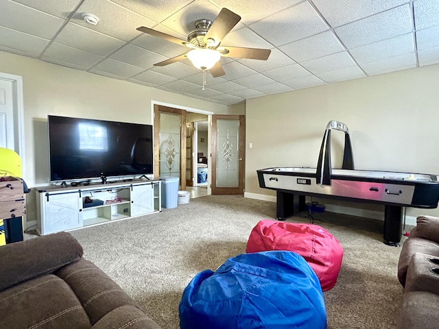 carpeted living room featuring ceiling fan and a drop ceiling