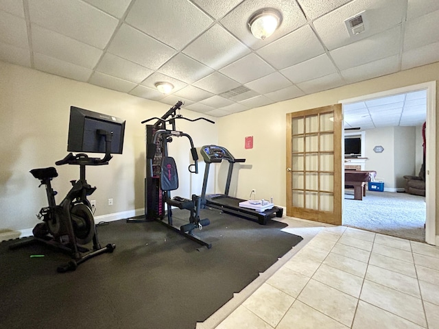 workout room with a paneled ceiling and tile patterned floors