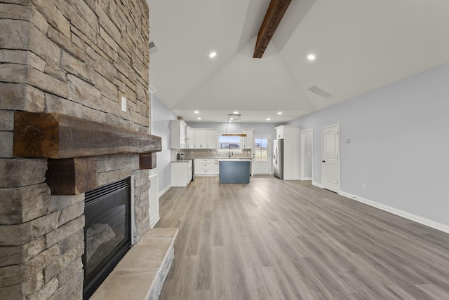 204 Max Cavnes Rd, Danville, KY 40422 - unfurnished living room featuring visible vents, baseboards, beamed ceiling, a stone fireplace, and light wood-style floors
