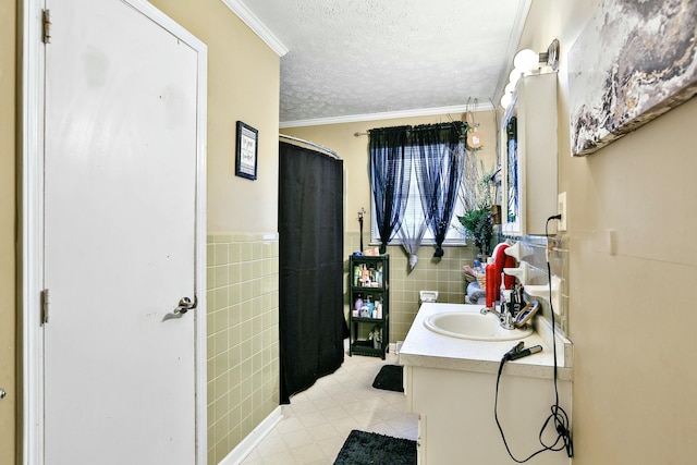 full bathroom with vanity, tile patterned floors, crown molding, a textured ceiling, and tile walls