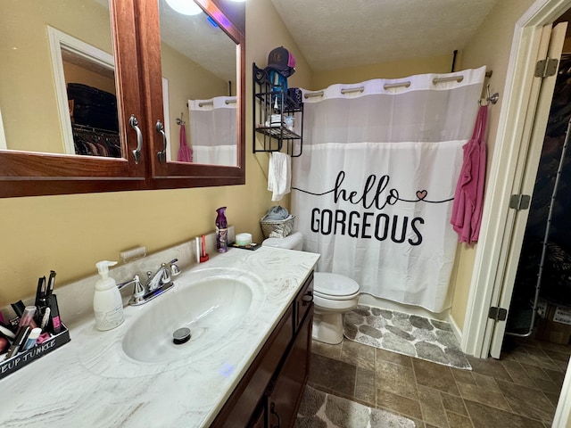 full bath featuring a textured ceiling, stone finish flooring, toilet, and vanity