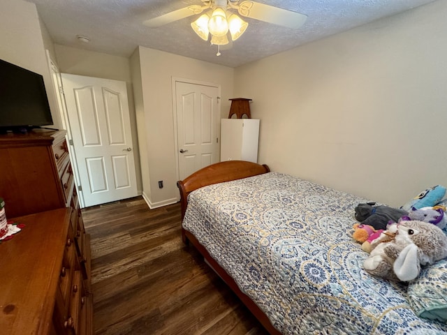 bedroom with dark wood-style floors, a textured ceiling, baseboards, and a ceiling fan