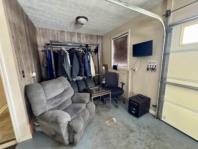 interior space with concrete flooring, wood walls, a textured ceiling, and a garage