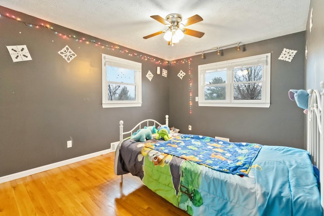 bedroom featuring ceiling fan, hardwood / wood-style flooring, and a textured ceiling