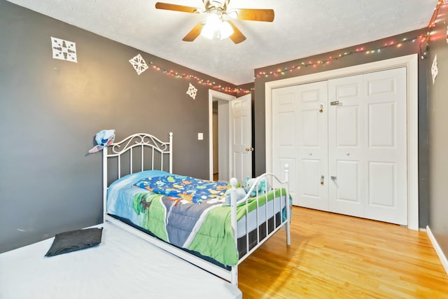 bedroom with ceiling fan, wood-type flooring, a closet, and a textured ceiling