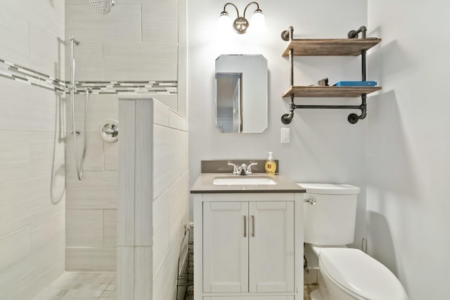 bathroom with vanity, tiled shower, and toilet