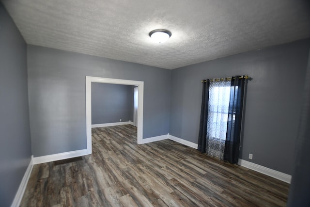 unfurnished room with dark wood finished floors, a textured ceiling, and baseboards