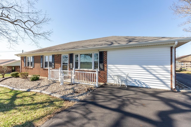 ranch-style home featuring aphalt driveway and brick siding