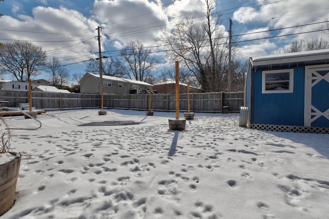 yard layered in snow featuring a fenced backyard and an outdoor structure