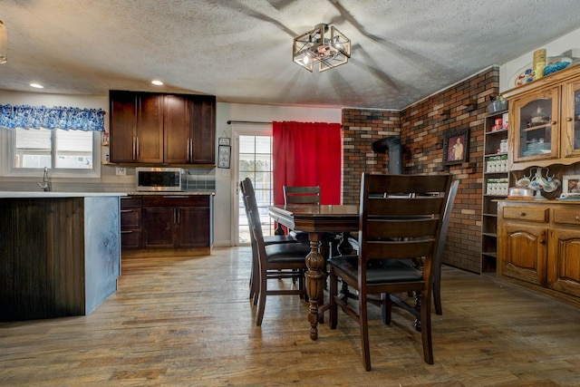 dining area with a textured ceiling, brick wall, light wood-type flooring, and recessed lighting