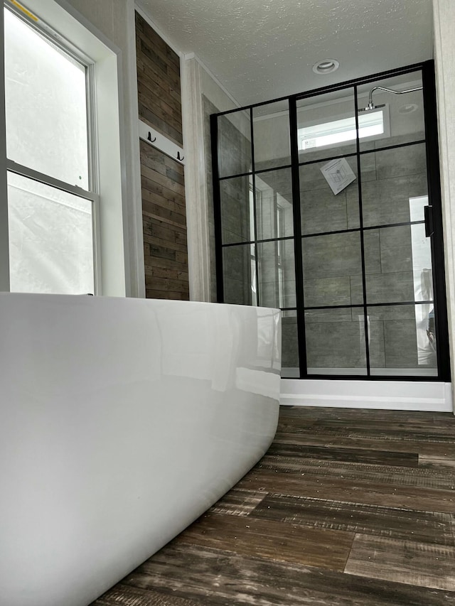 bathroom with wood walls, wood-type flooring, and a textured ceiling