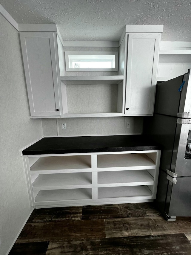 details with white cabinets, black refrigerator, dark hardwood / wood-style flooring, and a textured ceiling